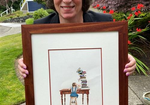 Representative Laurie Dolan holding framed artwork &quot;Toppling Books&quot;